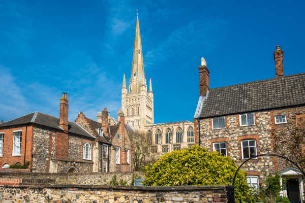 A low angle view of Norwich. Norwich Cathedral can be seen prominently in the centre between two buildings.