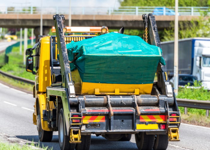 A rear view of a skip lorry travelling down a motorway